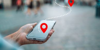 Hand holding a smartphone showing a navigation map with a dotted route between two pinned locations