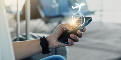 Hand wearing a smartwatch holding a smartphone displaying a flight-tracking app with an airplane icon